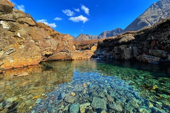 A Fairy Pools pool so clear that every stone on the bottom shows, red rock on the banks and the Cuillin behind