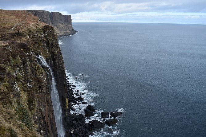 The Kilt Rock cliffs from the viewpoint railing, the waterfall dropping to the rocks and the coast running north