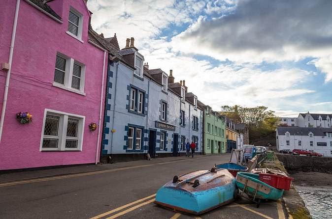 The painted houses on Portree's quayside close up, a pink house at the end of the row and upturned boats on the slipway