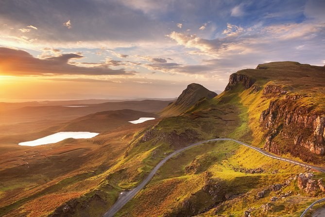 The Quiraing at sunset, the road winding up under the landslip cliffs and a lochan catching the light below