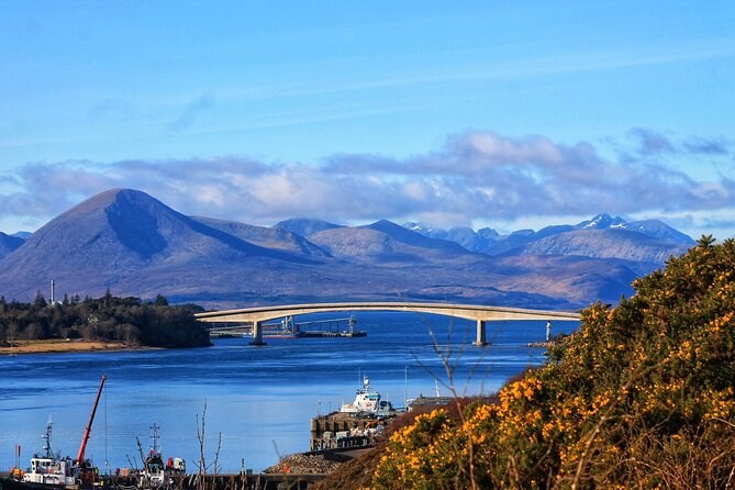 The Skye Bridge from the mainland side, the harbour at Kyle below and the hills of Skye behind, gorse in flower in the foreground
